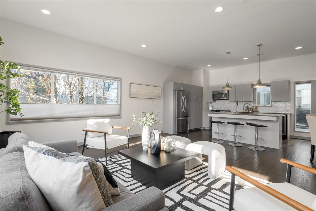 Open-concept living space featuring wood-finish flooring, recessed lighting, and a kitchen island with stone countertops