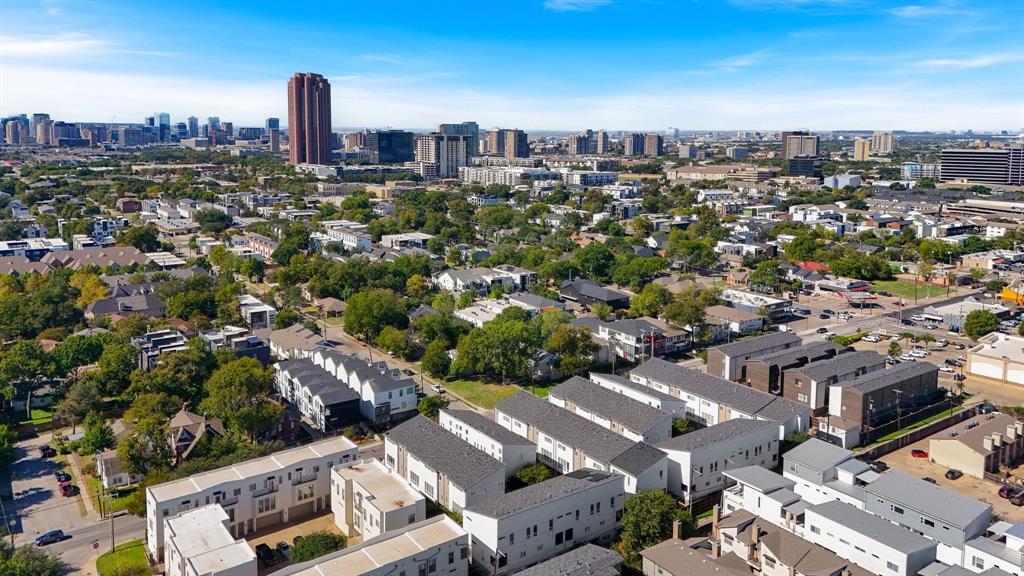 Aerial perspective of an urban neighborhood featuring multi-story residential structures with pitched rooflines and dense mature tree cover