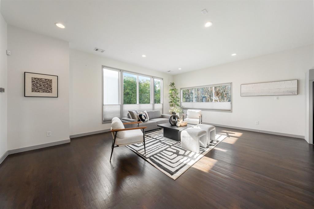 Open living area featuring dark wood-finish flooring, recessed lighting, and expansive windows