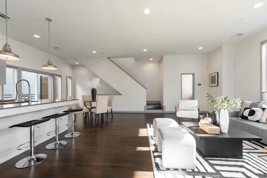 Open-concept interior featuring dark wood-finish flooring, recessed lighting, a kitchen island with stone countertop, and pendant lighting