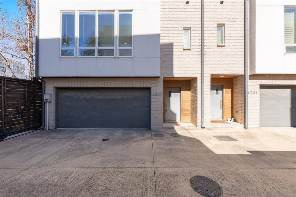 Contemporary multi-level exterior featuring light brick masonry, wood-accented recessed entryways, large multi-pane windows, and private attached garages