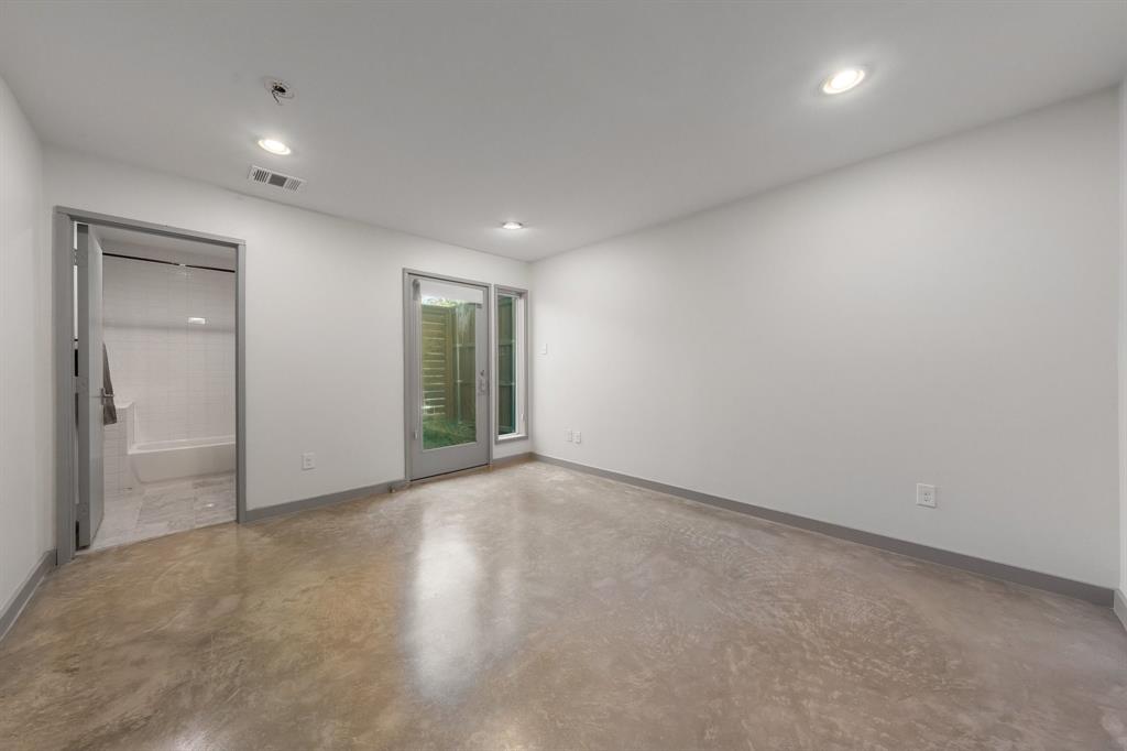 Polished concrete flooring, recessed lighting, neutral wall palette, glass-panel entry door, and matching interior trim