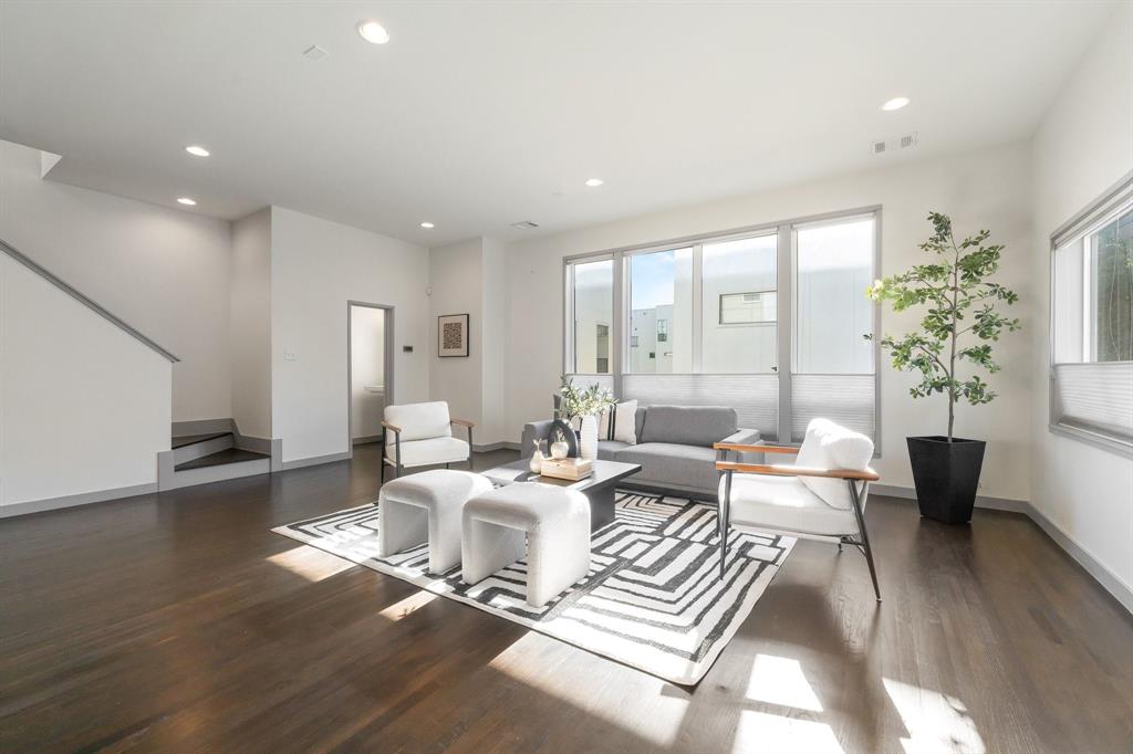 Living area featuring wood-finish flooring, recessed lighting, and large windows with cellular shades