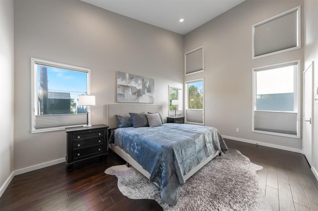 Vaulted ceilings, dark-toned wood-finish flooring, and multiple windows with integrated cellular shades