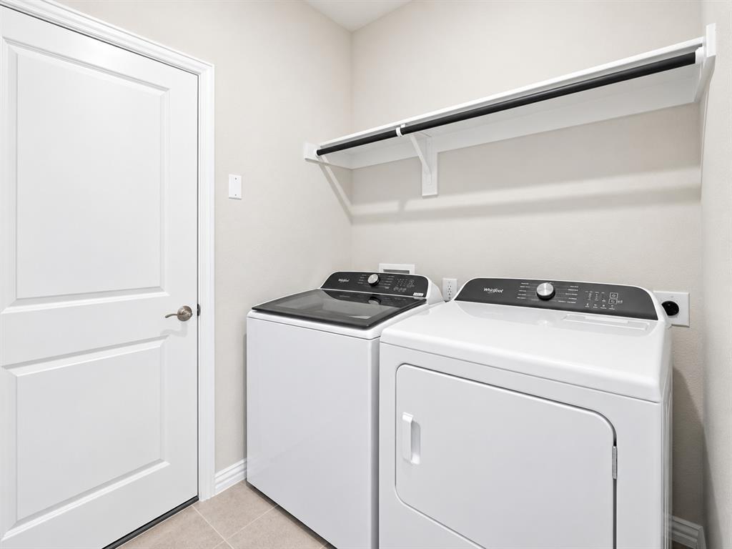 Laundry area with a white paneled door, light-toned wall paint, and tile flooring