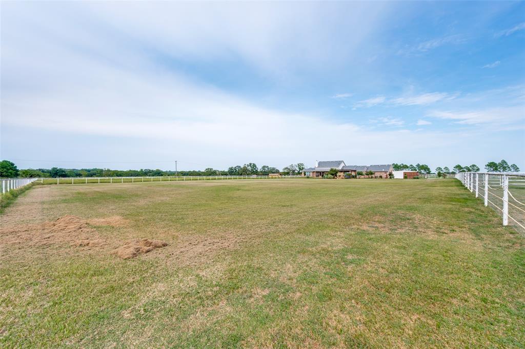Expansive pasture land featuring perimeter post-and-rail fencing and open terrain