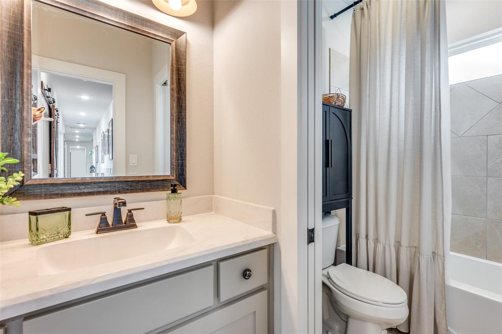 Bathroom featuring a vanity with a neutral-toned countertop, undermount sink, and oil-rubbed bronze faucet, paired with a framed mirror and a tile-surround tub