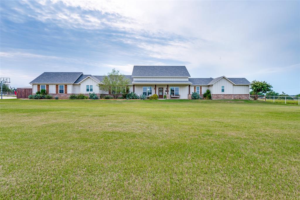 Single-story ranch exterior featuring board-and-batten siding, a brick facade, shingle roofing, and an expansive lawn