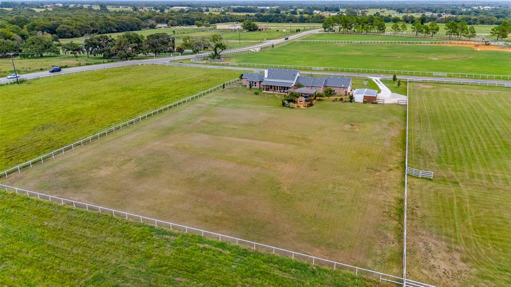 Expansive acreage featuring perimeter white fencing, a multi-section roofline, paved driveway, and established landscape grounds
