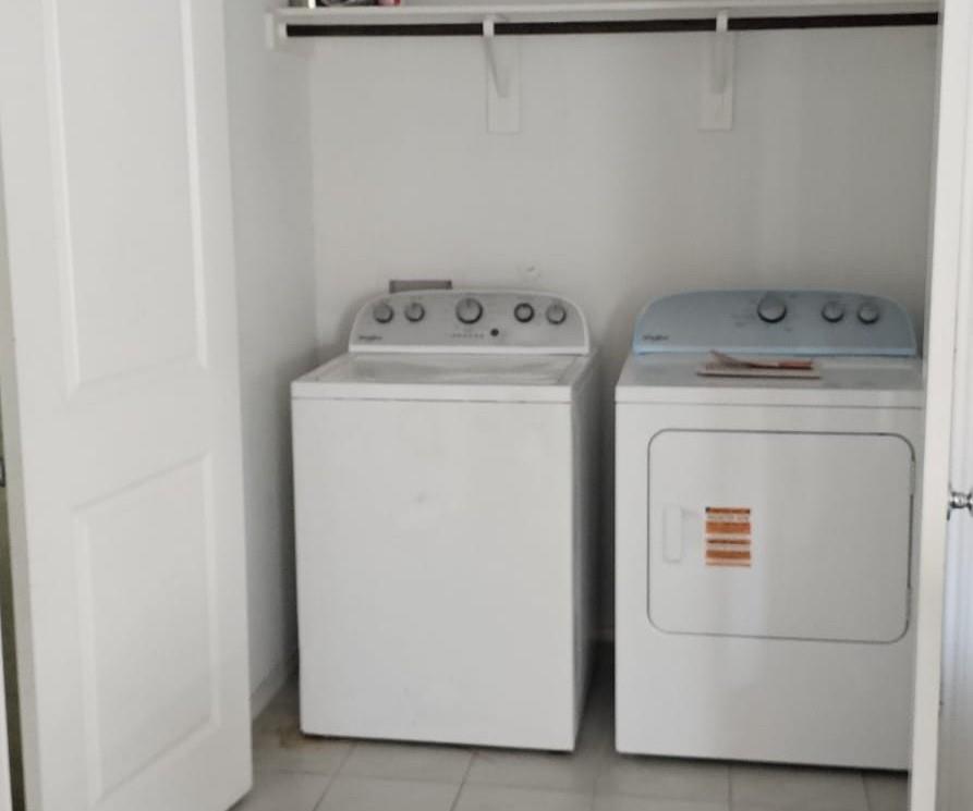 Laundry room featuring light tile patterned floors and washing machine and clothes dryer