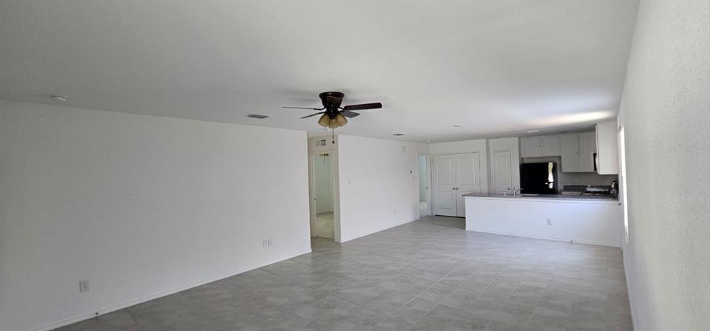 Unfurnished living room with a ceiling fan and baseboards