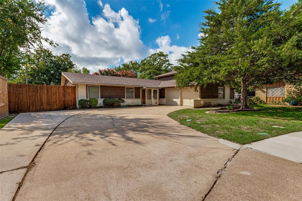 Single-story exterior featuring light-toned brick masonry, horizontal wood-toned siding, a concrete driveway, and an attached garage