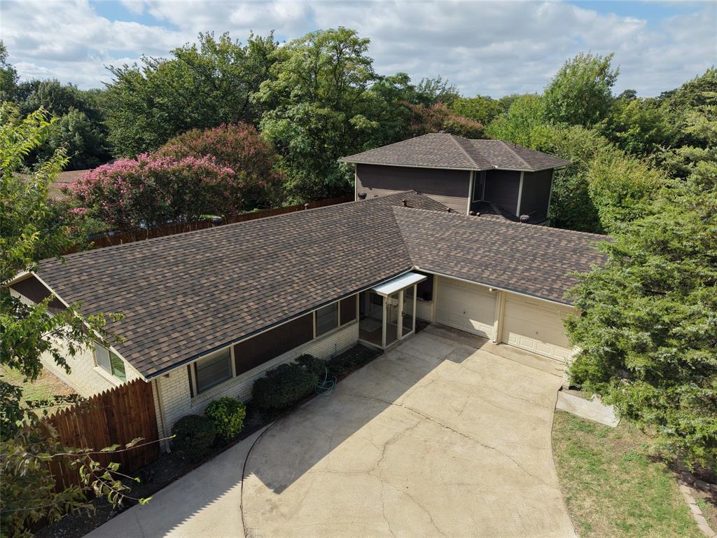 Multi-level exterior featuring a brick and horizontal siding facade, composite shingle roof, two-car garage, and mature tree landscaping