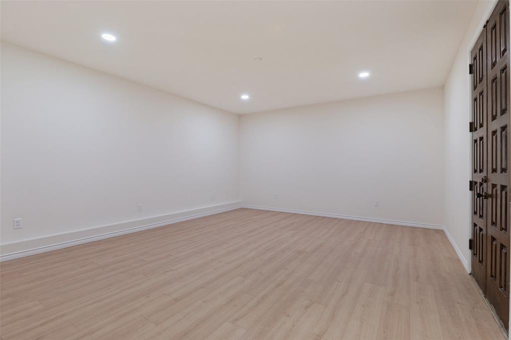 Neutral-toned interior space featuring wood-finish flooring, recessed lighting, and dark-stained double doors