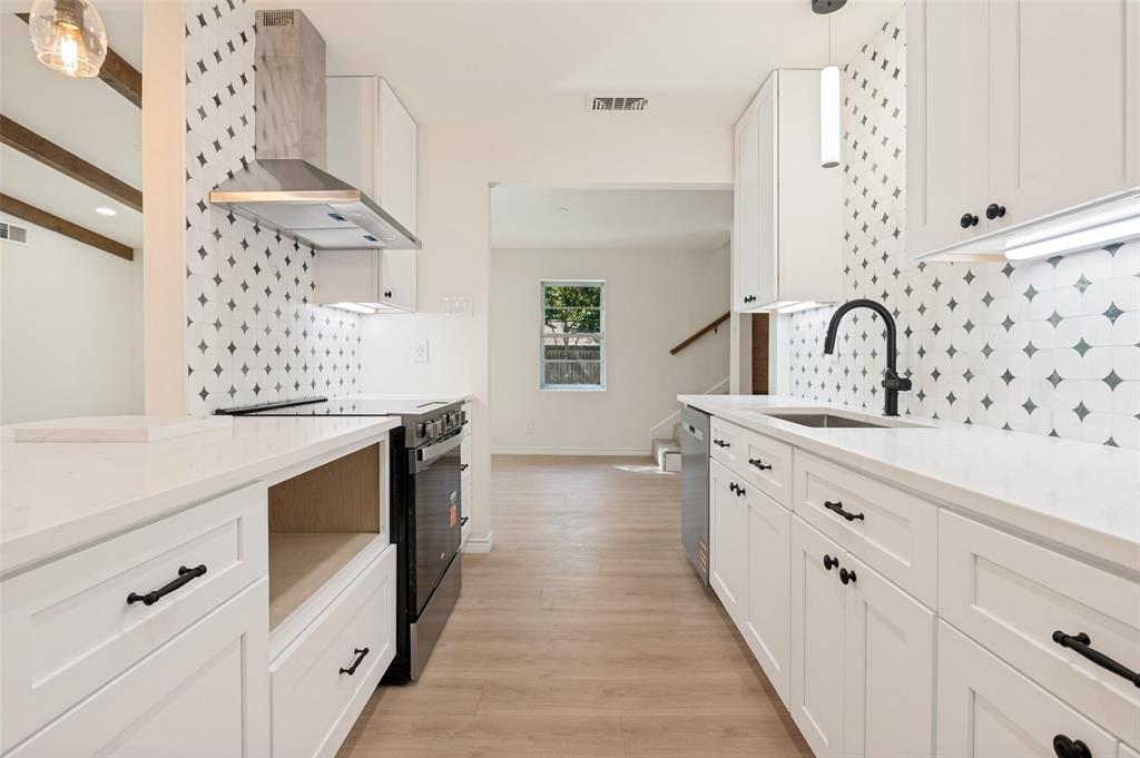 Kitchen featuring white shaker-style cabinetry, solid-surface countertops, decorative geometric backsplash tile, wood-finish flooring, and a stainless steel chimney-style range hood