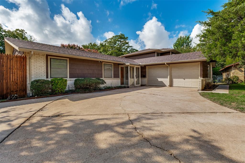 Multi-level exterior featuring a combination of brick and wood-shingle siding, a two-car garage, and a wood privacy fence