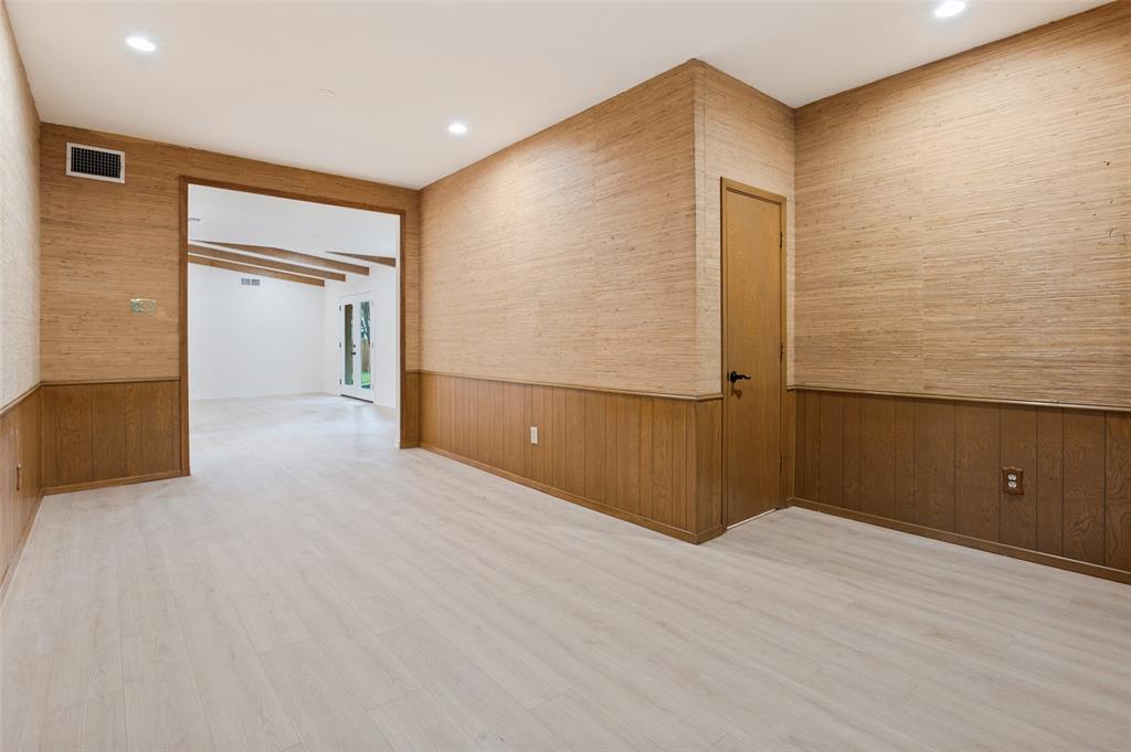 Textured wall coverings, horizontal wood-panel wainscoting, light wood-finish flooring, and recessed ceiling lighting