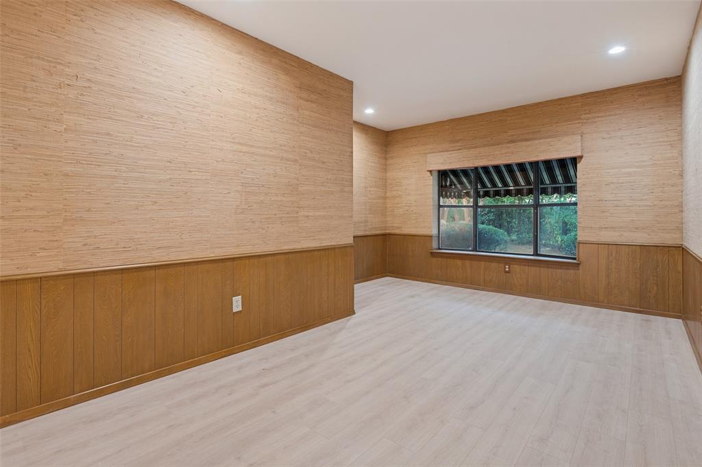 Interior room featuring textured wall coverings, wood-panel wainscoting, wood-finish flooring, recessed lighting, and a multi-pane window with a fabric valance
