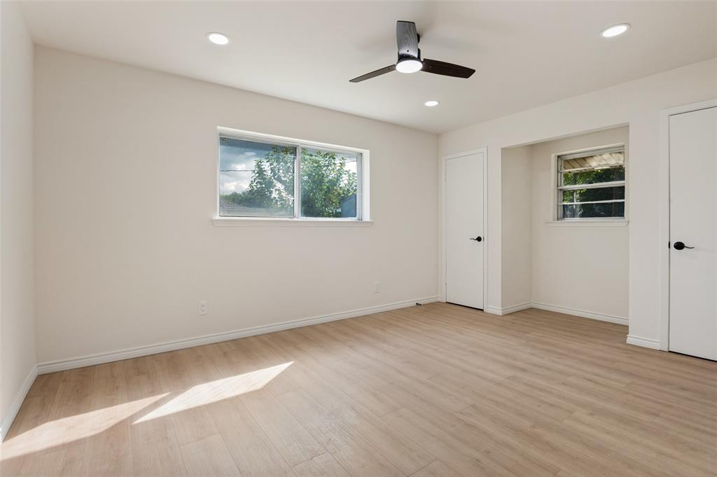 Interior space featuring wood-finish flooring, recessed lighting, a ceiling fan with integrated lighting, dual windows, and interior doors with matte black hardware