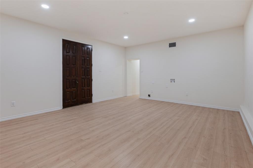 Interior space featuring neutral wall tones, wood-finish flooring, recessed lighting, and a dark-stained wood-paneled double door