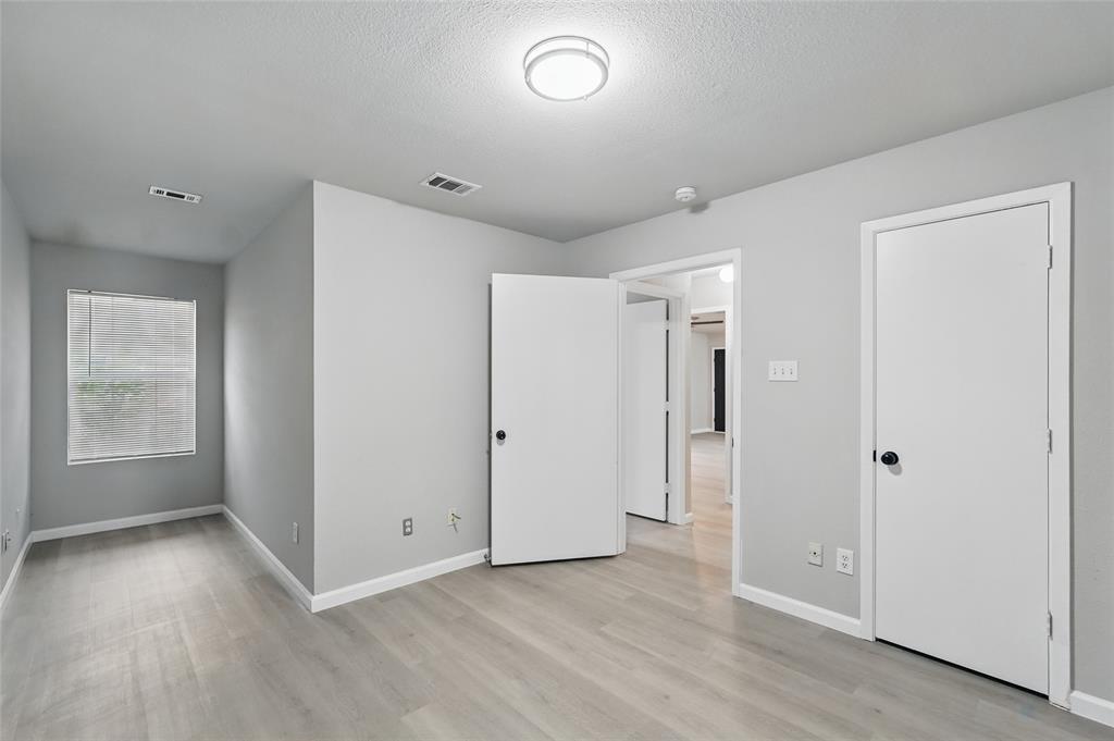 Neutral-toned interior featuring wood-finish flooring, crisp white walls, flush-mount lighting, and solid-core interior doors