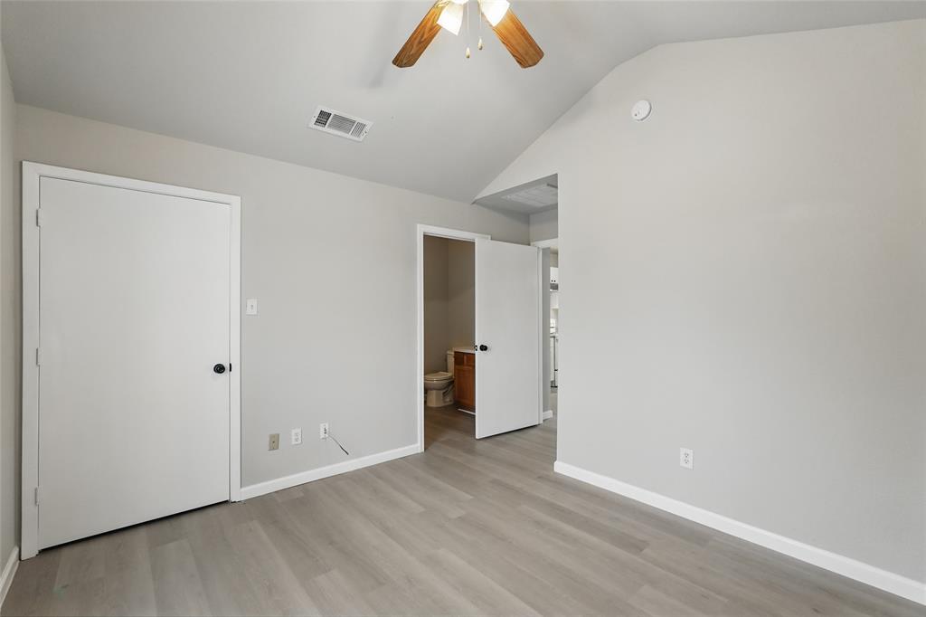 Vaulted ceilings, wood-finish flooring, and a ceiling-mounted light fixture with a fan