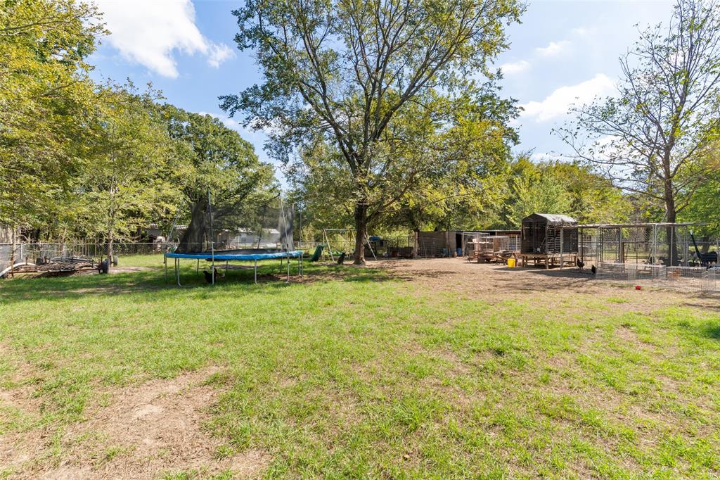 Expansive lot featuring mature trees, perimeter wire fencing, and multiple external structures