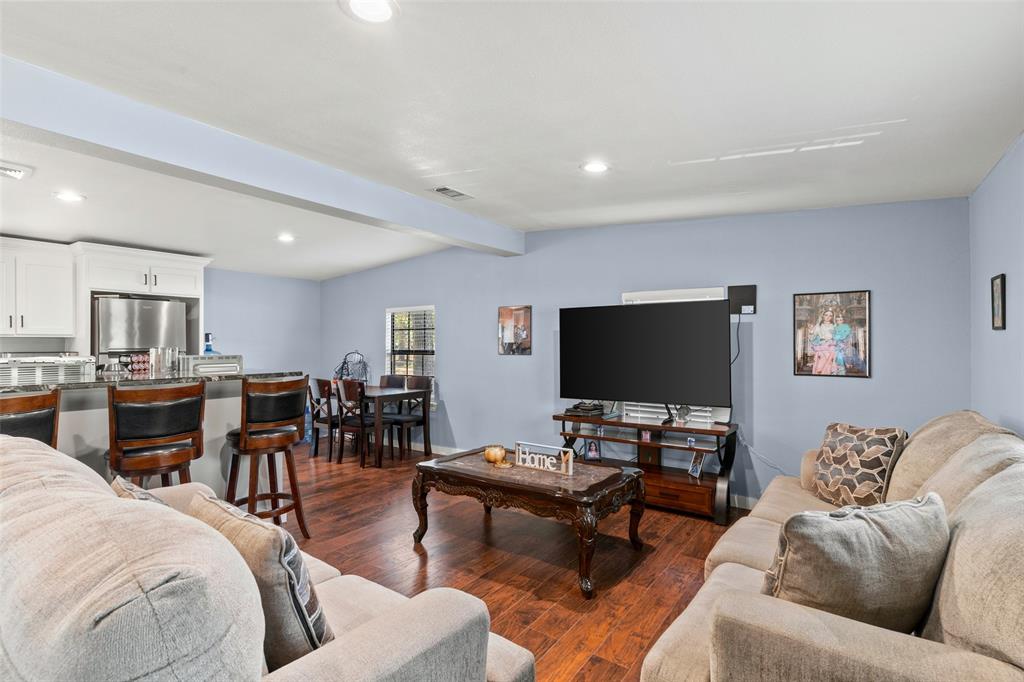 Open-concept interior featuring wood-finish flooring, recessed lighting, and a kitchen breakfast bar with stone-finish countertops