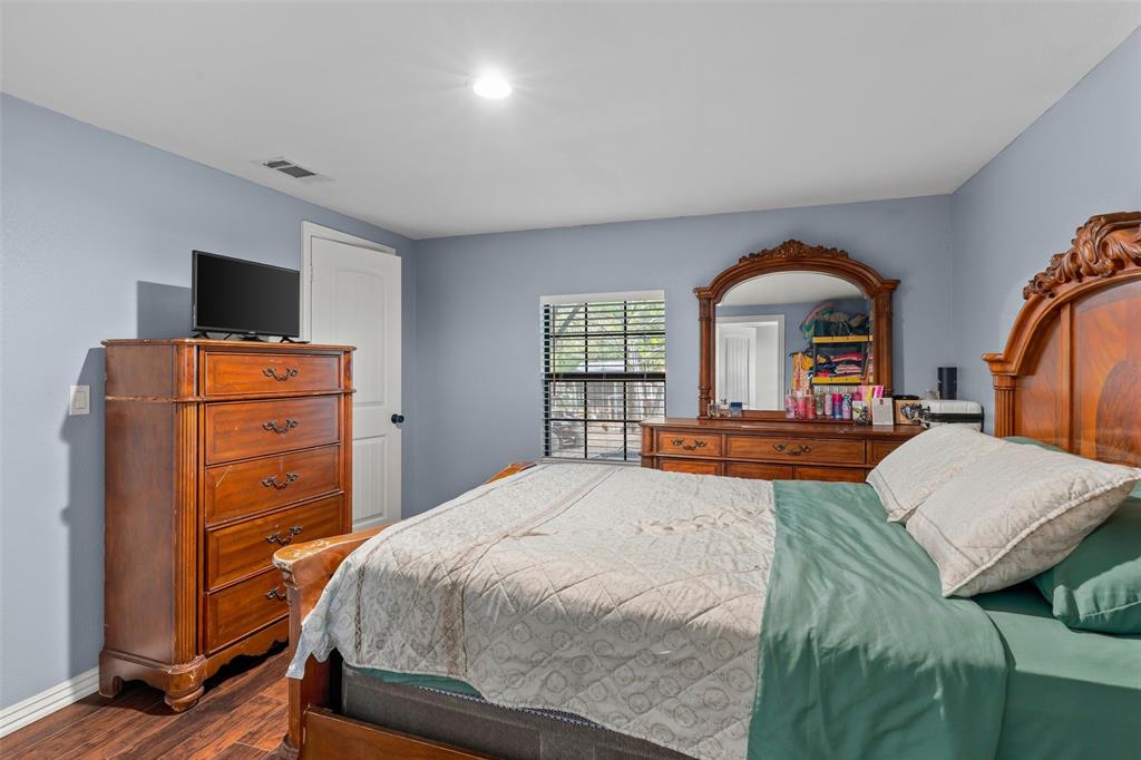 Bedroom featuring wood-finish flooring, a recessed lighting fixture, and a window with horizontal blinds