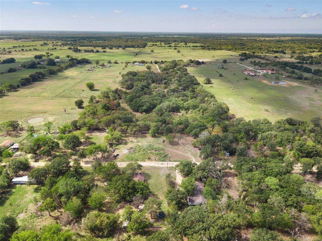 Aerial perspective of expansive acreage featuring dense clusters of mature trees, open pastureland, and established rural topography