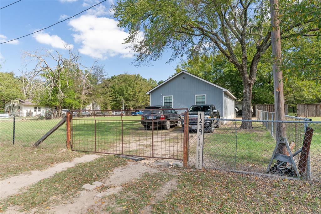 Single-story residence with vertical siding, gable roof, metal perimeter fencing, and dual-panel metal gate