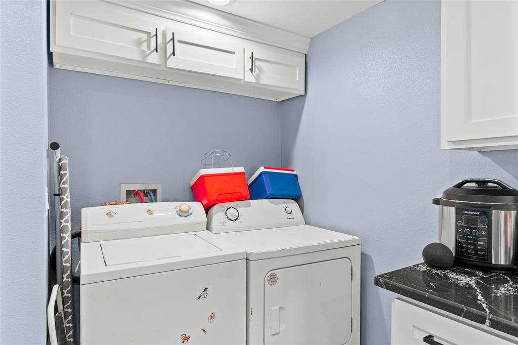 Utility space featuring white shaker-style wall-mounted cabinetry with matte black hardware, stone-finish countertops, and recessed ceiling lighting