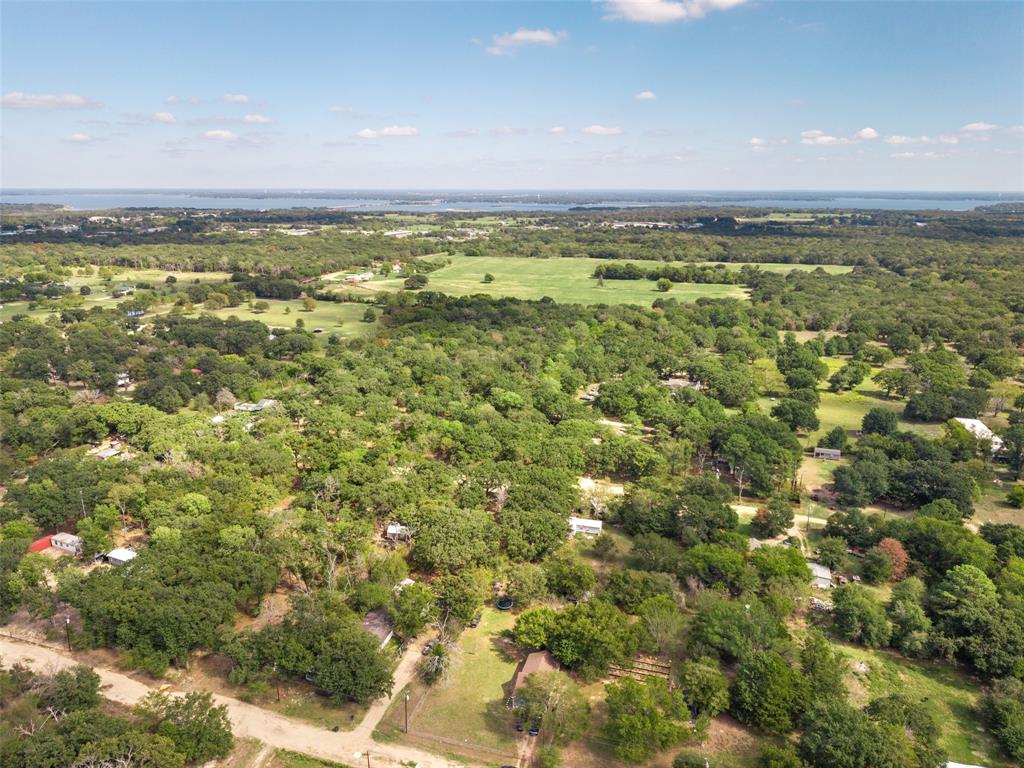 Aerial perspective featuring expansive wooded acreage, mature canopy trees, and an open grass clearing