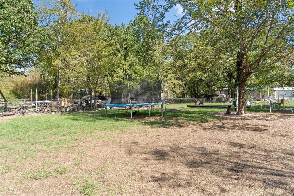 Expansive lot featuring mature trees, partial grass lawn, and a perimeter chain-link fence