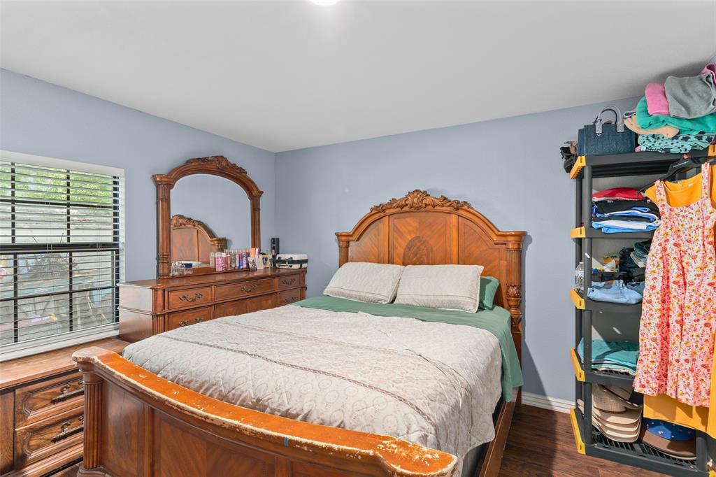 Bedroom featuring wood-finish flooring and a single-pane window with horizontal blinds