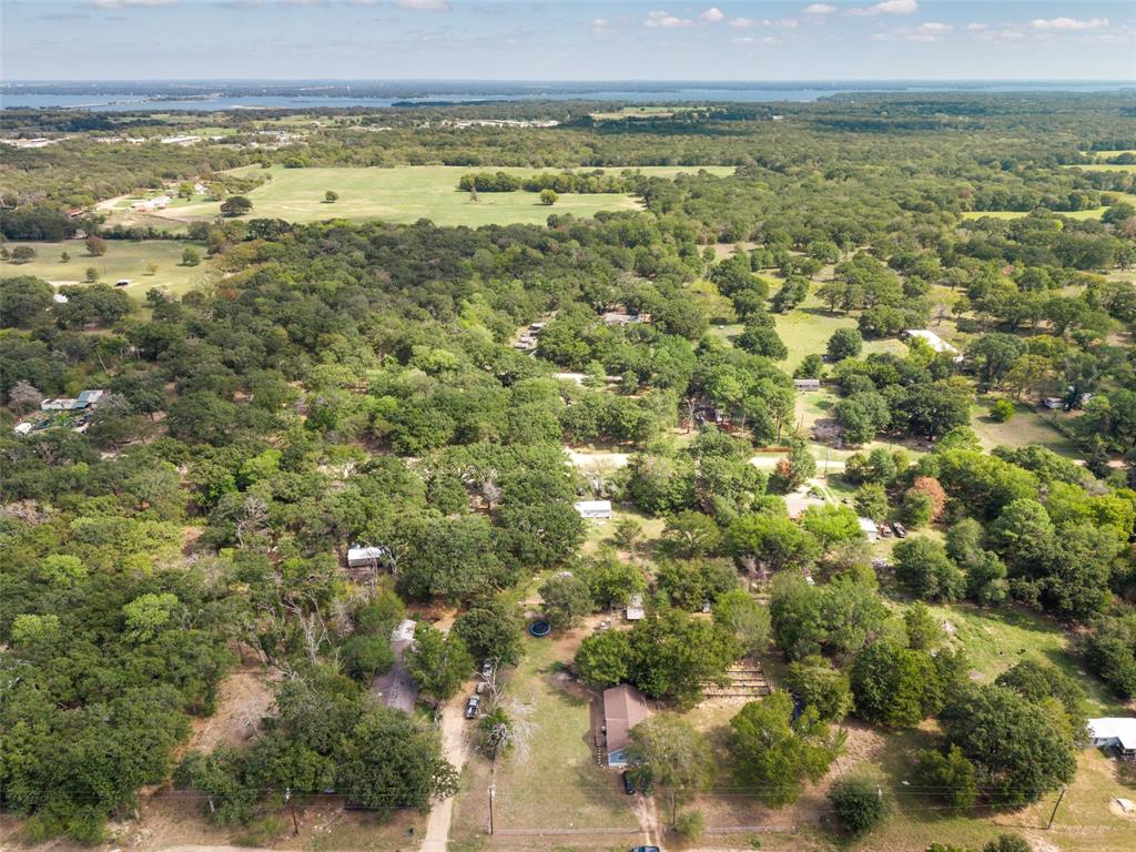 Aerial perspective of a sprawling parcel featuring expansive tree coverage, cleared open space, and distant water scenery