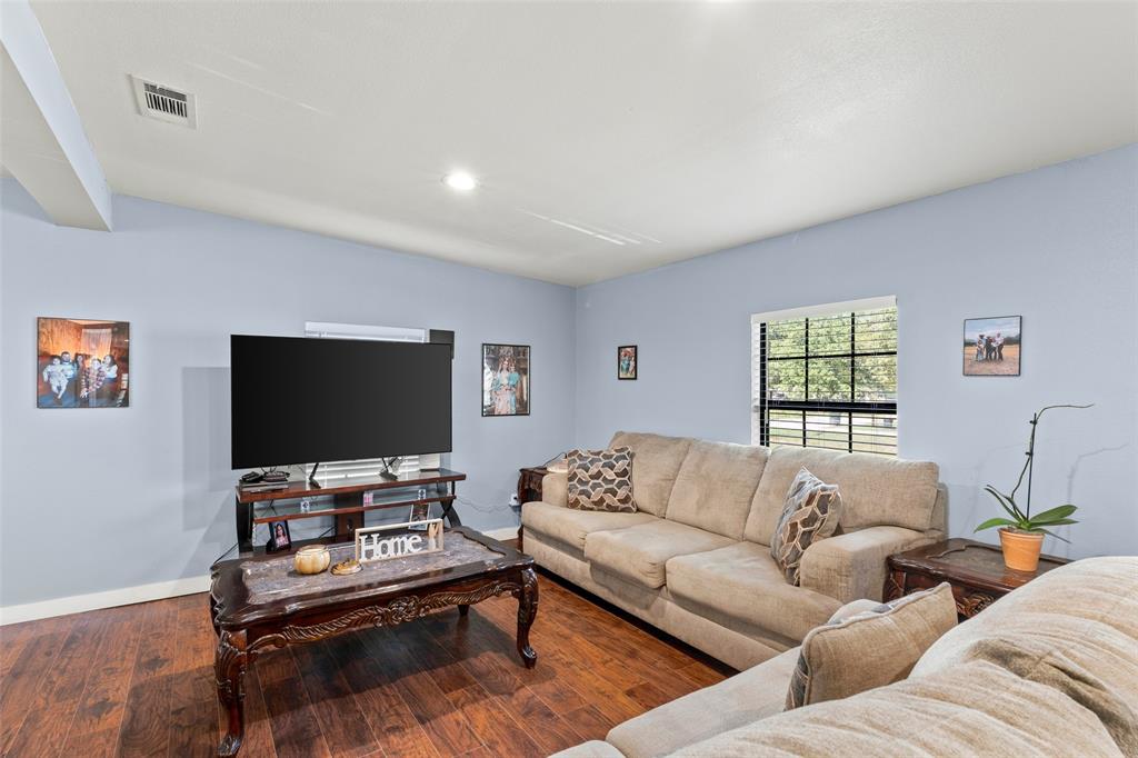 Room interior featuring wood-finish flooring, recessed lighting, and a window with a grid pattern