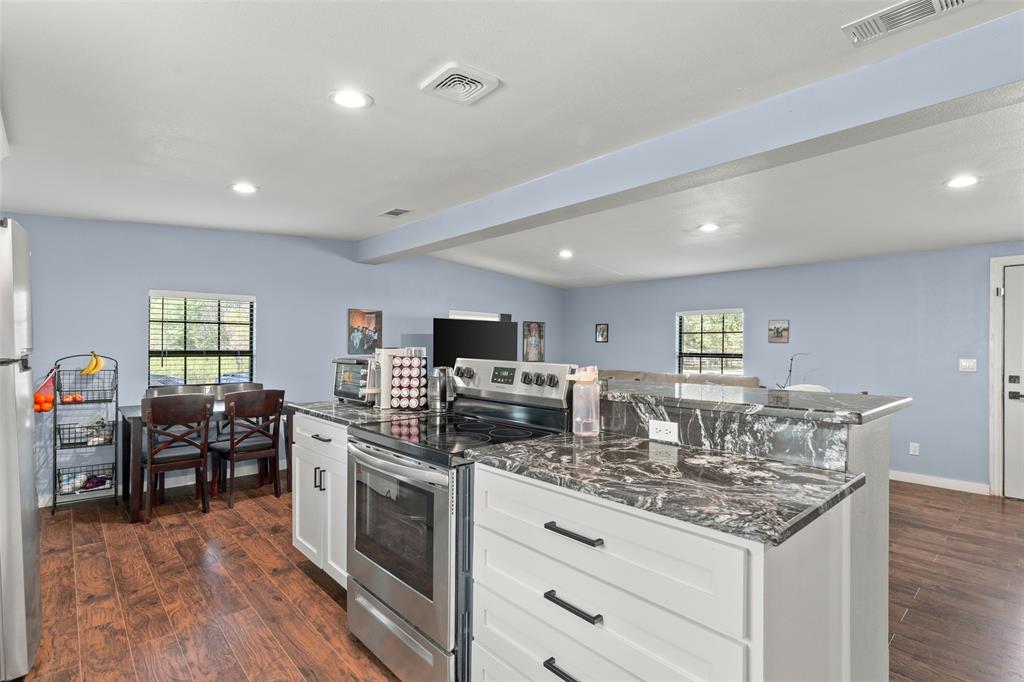 Kitchen featuring white cabinetry, stone-finish countertops, stainless steel appliances, and wood-finish flooring