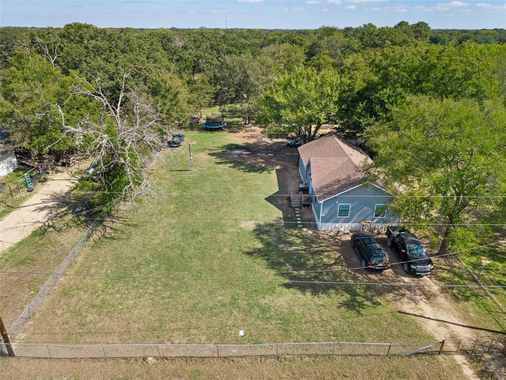Expansive lot featuring mature trees, a chain-link fenced perimeter, and a detached structure with a pitched shingle roof