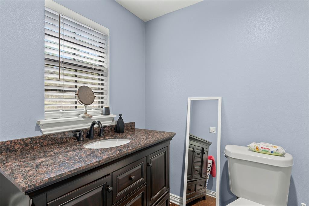 Dark wood cabinetry featuring raised-panel doors, stone-finish countertop, undermount sink with matte black faucet, and horizontal slat window blinds
