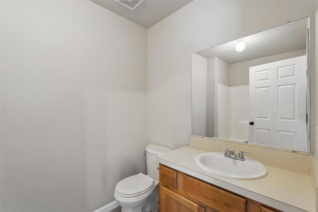 Full-width vanity with a wood-finish cabinet, integrated basin, dual-handle faucet, and large wall-mounted mirror
