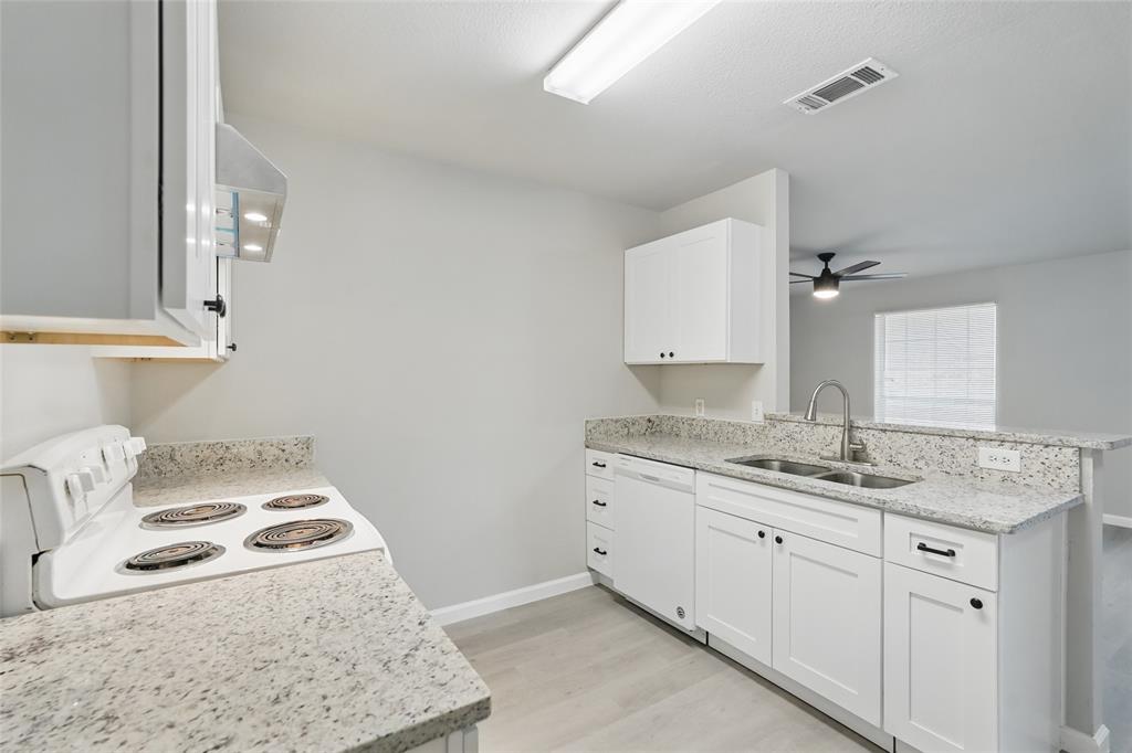 Kitchen featuring white shaker-style cabinetry, stone-finish countertops, stainless steel dual-basin sink with gooseneck faucet, integrated electric range, and wood-finish flooring