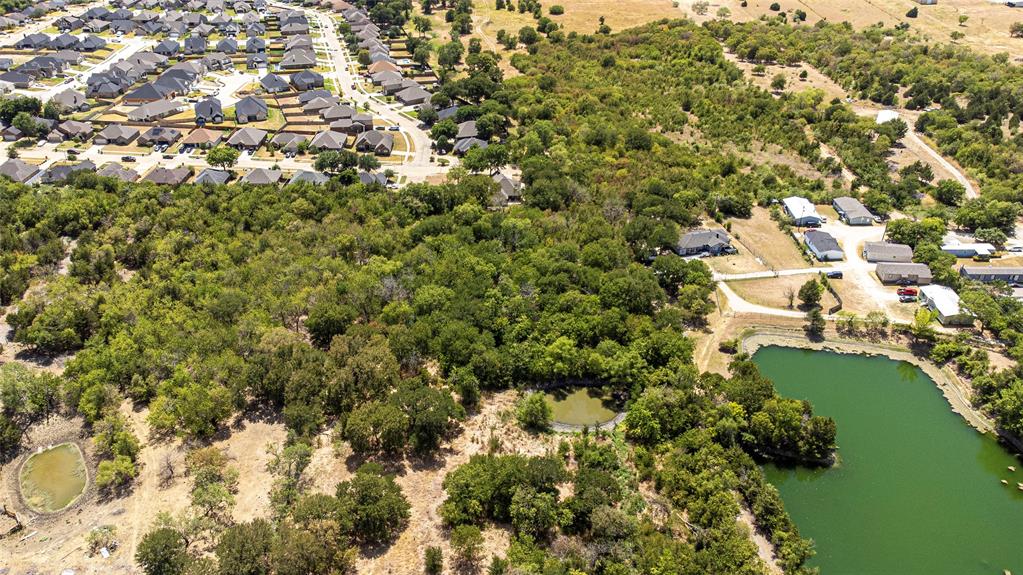 Aerial perspective of expansive acreage featuring mature trees, natural vegetation, and multiple water features