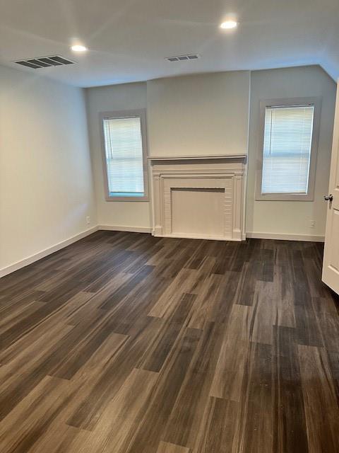 Wood-finish flooring, white decorative fireplace mantel, recessed ceiling lighting, and dual windows