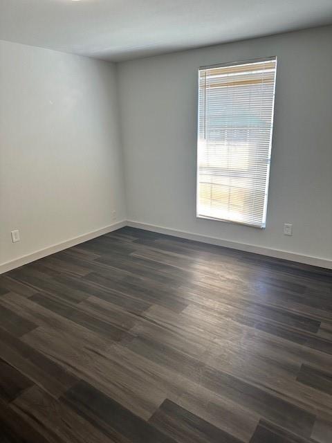Neutral-toned interior space featuring wood-finish flooring, crisp white walls, and a single window with horizontal blinds