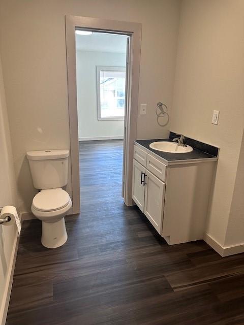 Bathroom featuring wood-finish flooring, a white vanity with dark hardware, a surface-mount sink with a chrome faucet, and a wall-mounted metal towel ring