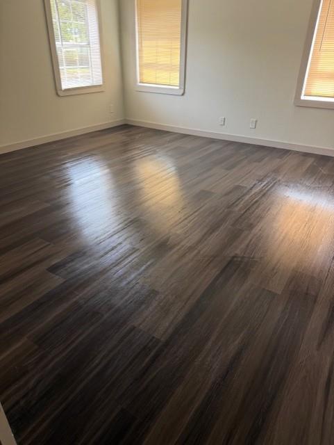 Wood-finish flooring, neutral wall tones, and multiple windows with integrated blinds