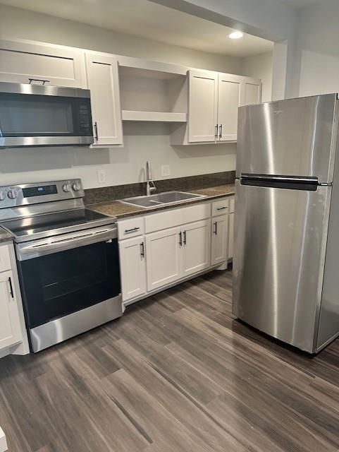 Kitchen featuring white shaker-style cabinetry, stainless steel appliances, stone-surface countertops, dual-basin sink with a gooseneck faucet, and wood-finish flooring