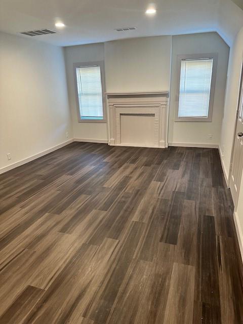 Wood-finish flooring, decorative fireplace mantle, dual windows, and recessed lighting