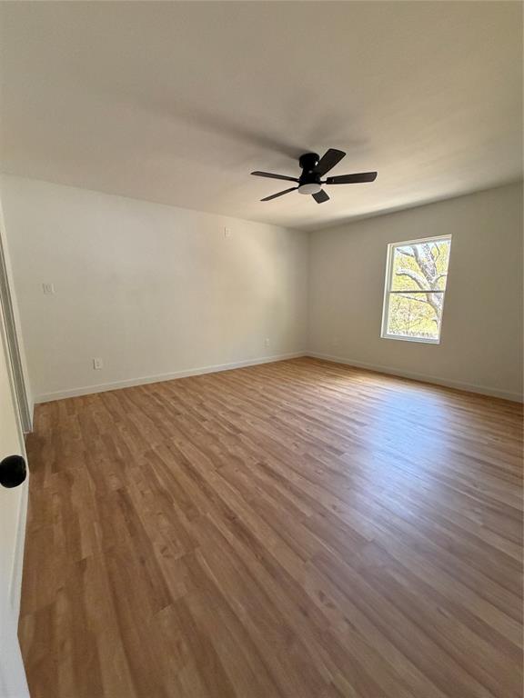 Interior room featuring wood-finish flooring, a single-hung window, and a matte black ceiling fan with integrated lighting